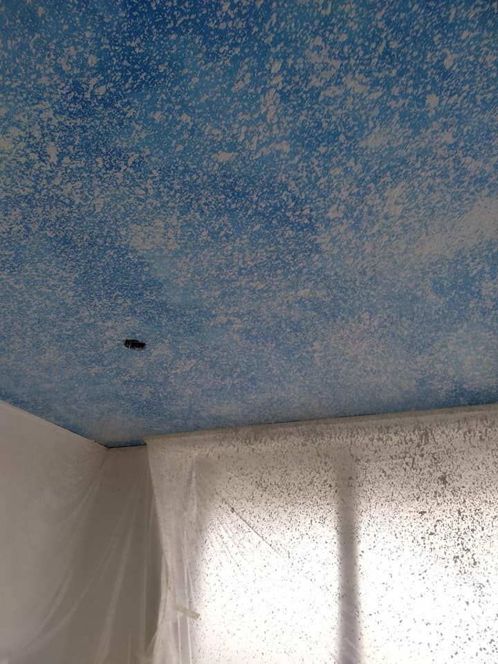 A room with a blue ceiling and white curtains.