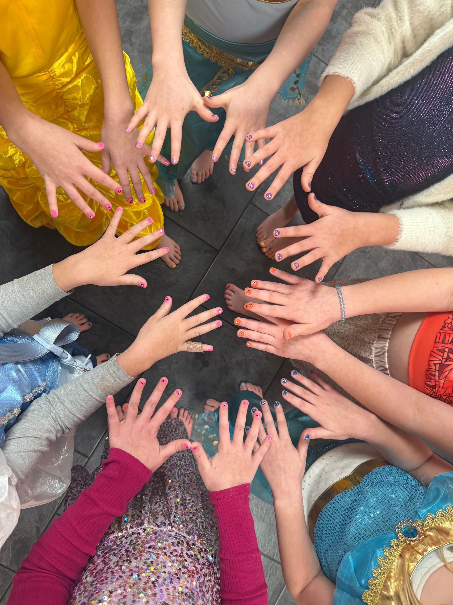 A group of children are holding their hands together in a circle.