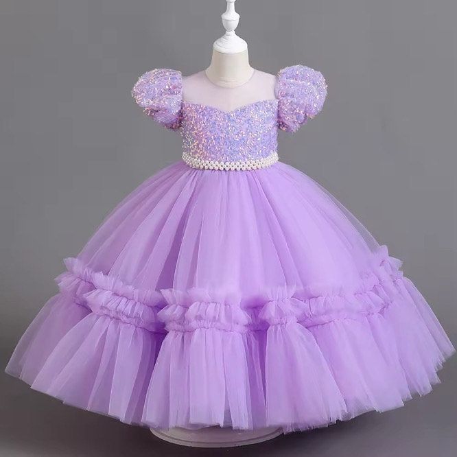 A little girl is wearing a purple dress on a mannequin.