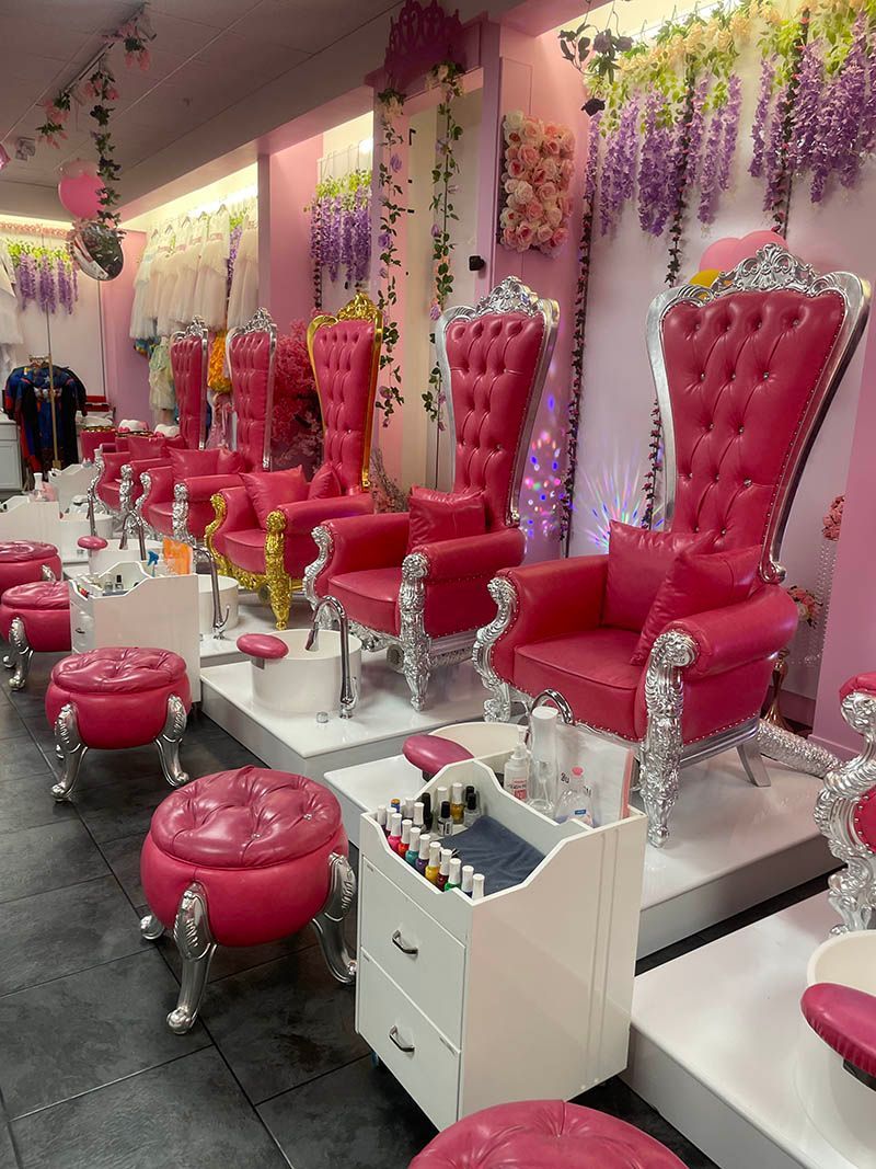 A nail salon with lots of pink chairs and ottomans.