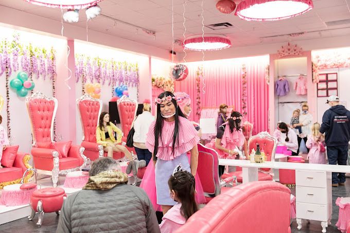 A girl is getting her hair cut in a pink salon.