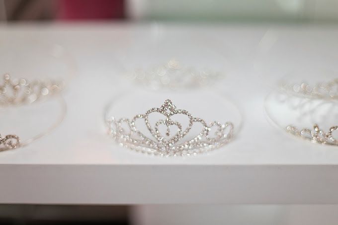 A row of tiaras sitting on top of a white shelf.