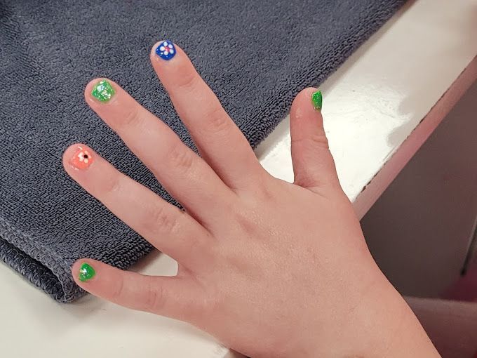 A child 's hand with nails painted in different colors
