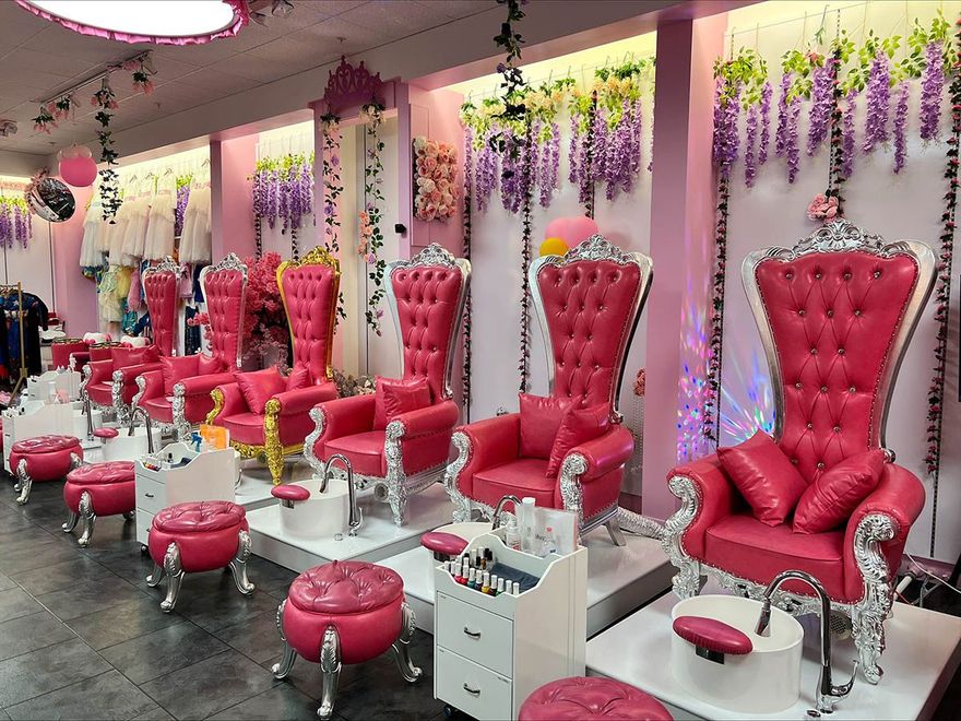 A nail salon with pink chairs and purple flowers on the walls.