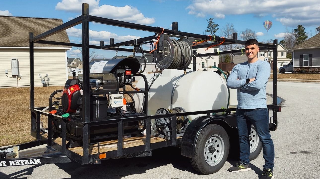 A man is standing in front of a trailer with a hose attached to it.