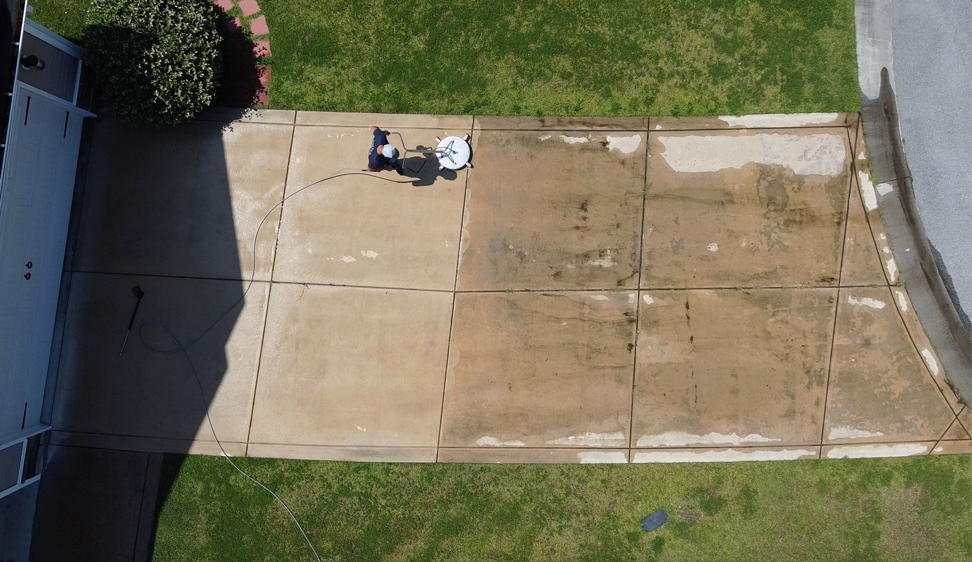 An aerial view of a concrete driveway next to a grassy yard.
