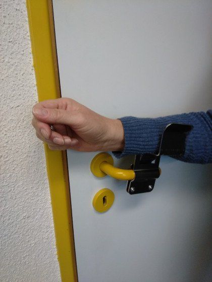 Eine Person öffnet eine Tür mit einem gelben Griff