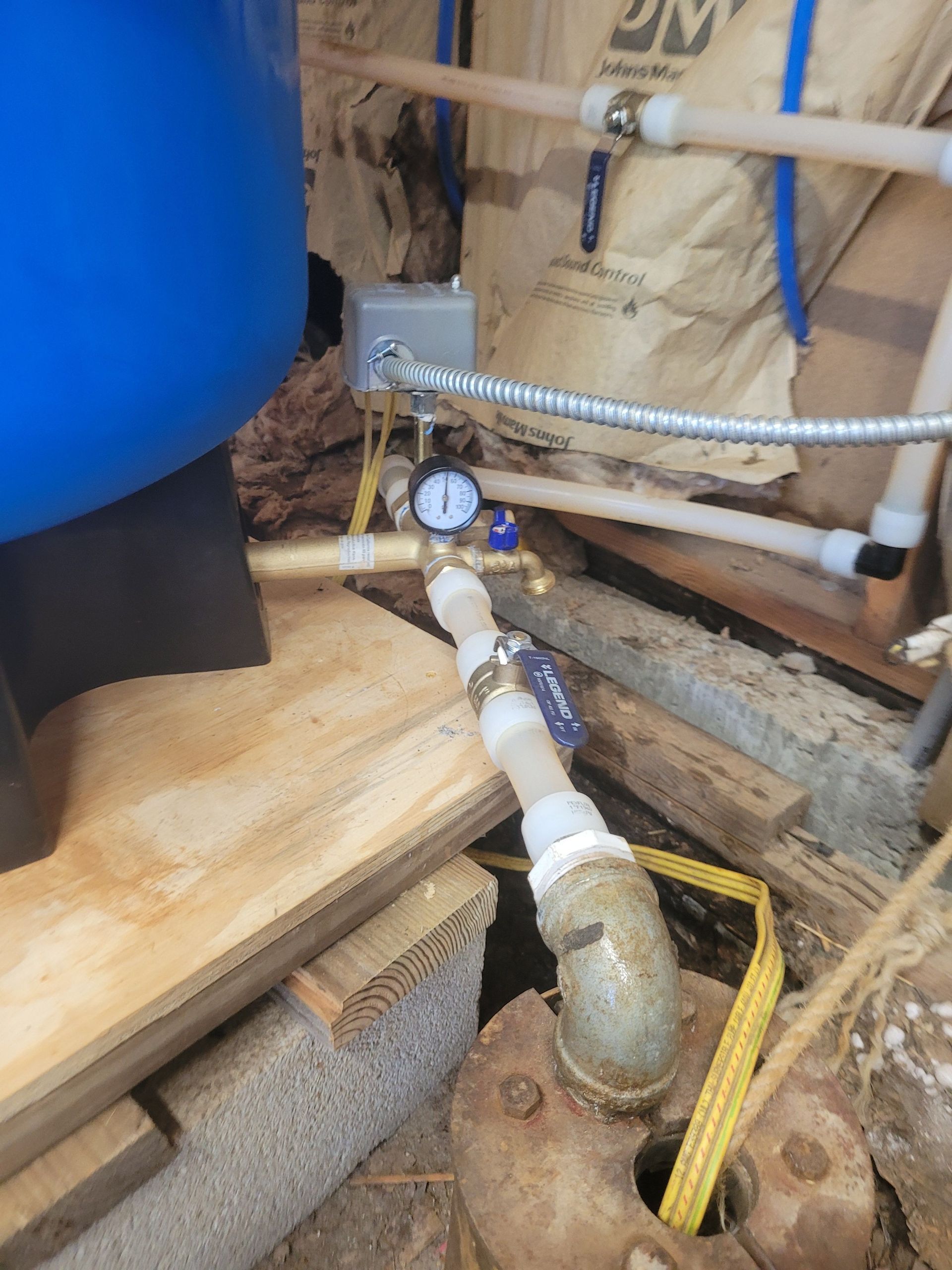 Water well system components: pressure tank, gauge, switch, piping.