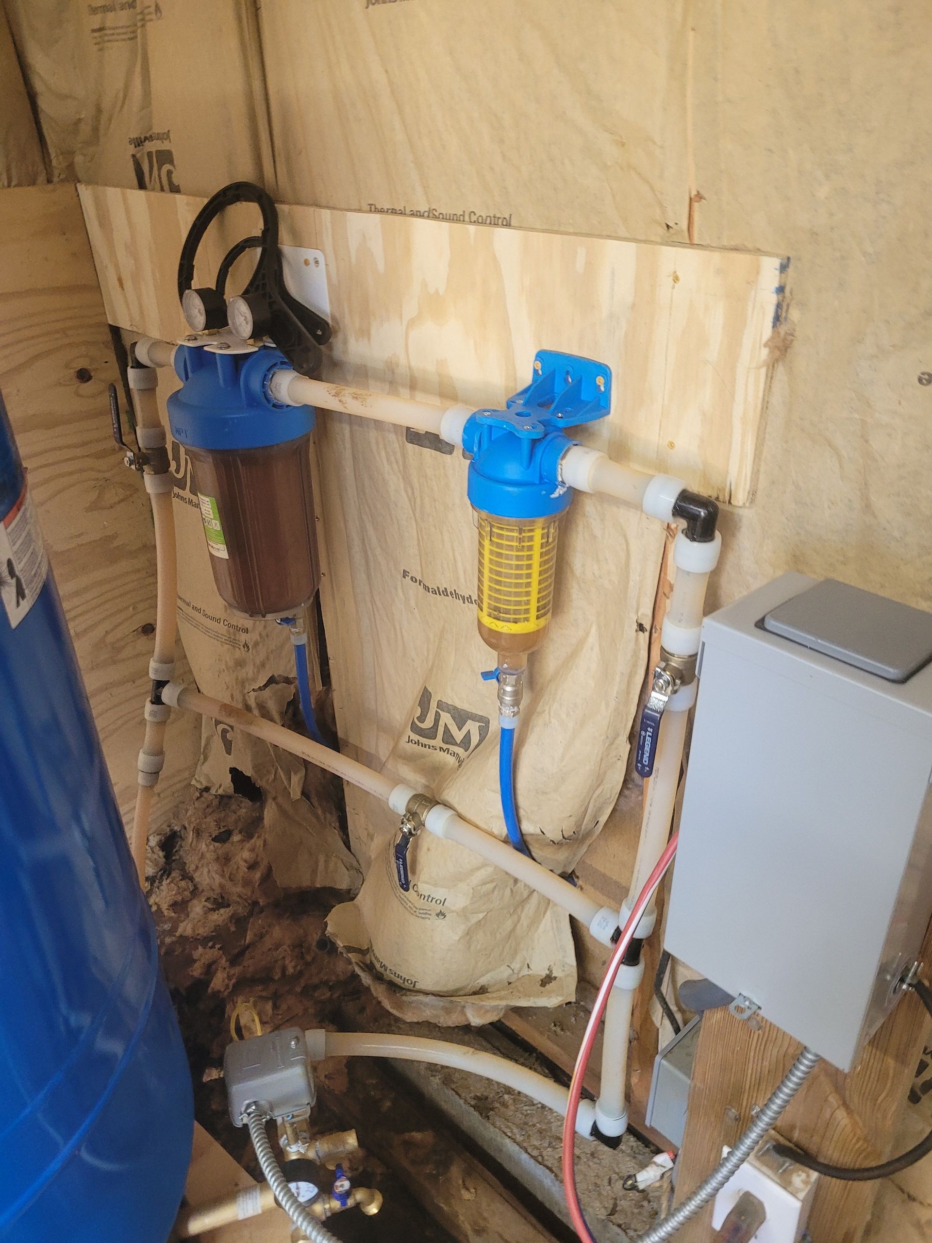 Water filtration system with blue and brown filters, installed on plywood.