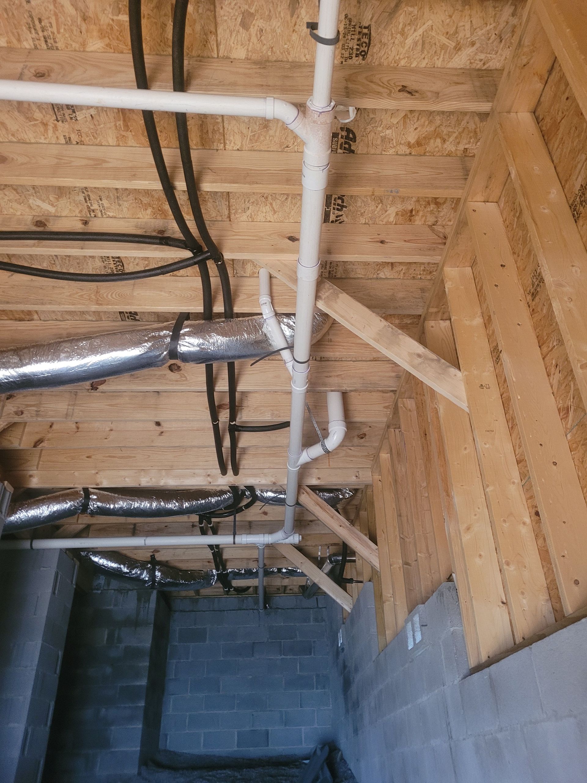 View of unfinished basement ceiling with plumbing, ductwork, and electrical wiring attached to wood framing.