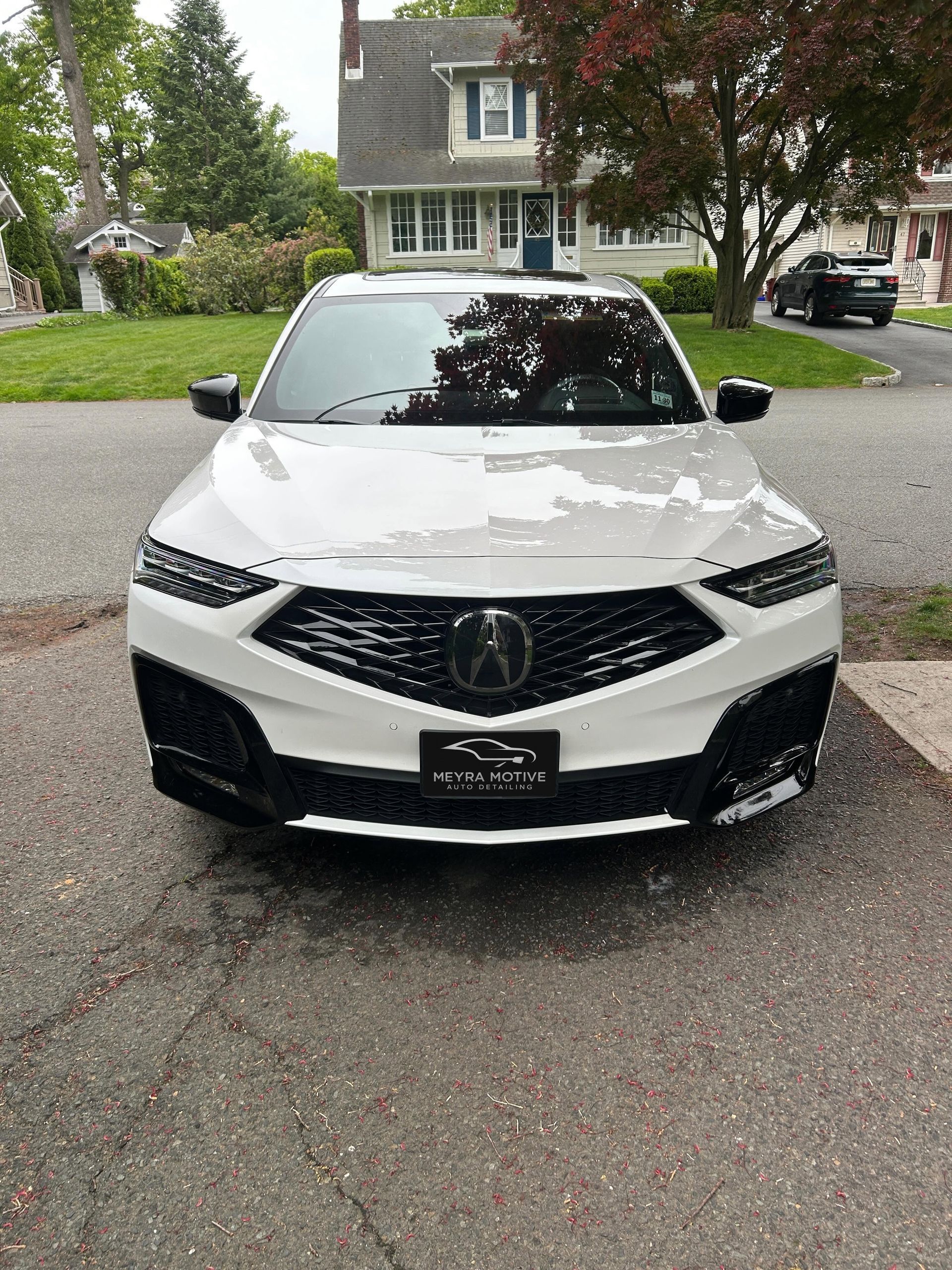 White Acura SUV parked on a suburban street in front of a house