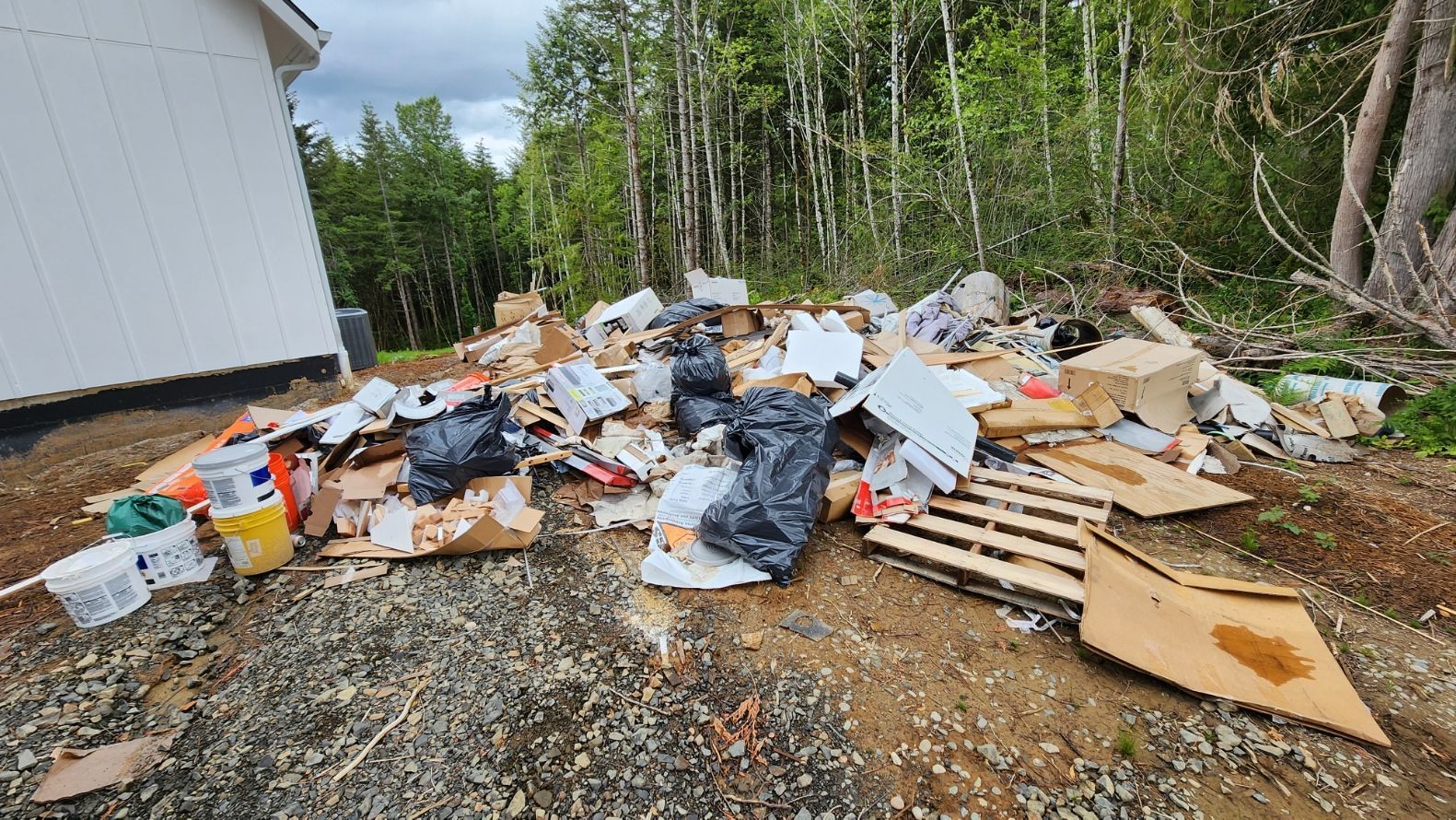 A pile of garbage is sitting on the ground in front of a white building.