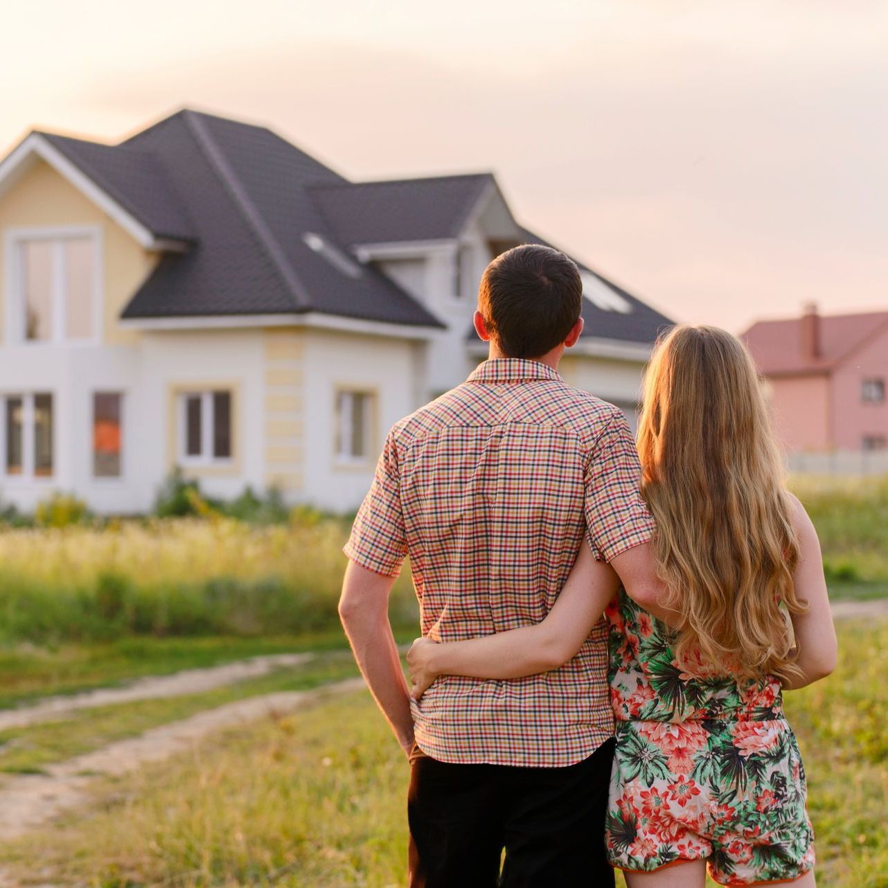 Un homme et une femme se tiennent devant une maison.