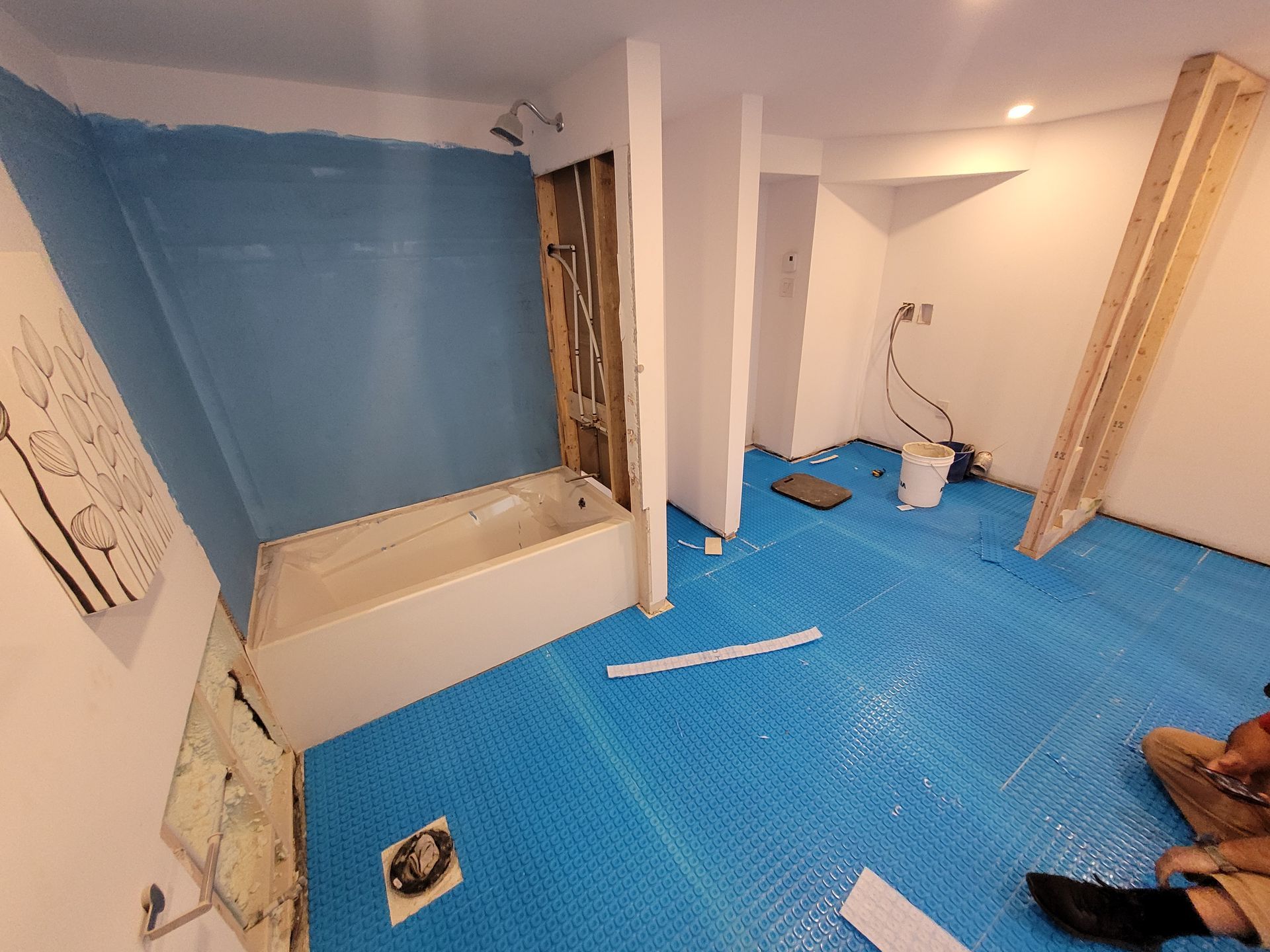 Une salle de bain avec une baignoire et un tapis bleu au sol.