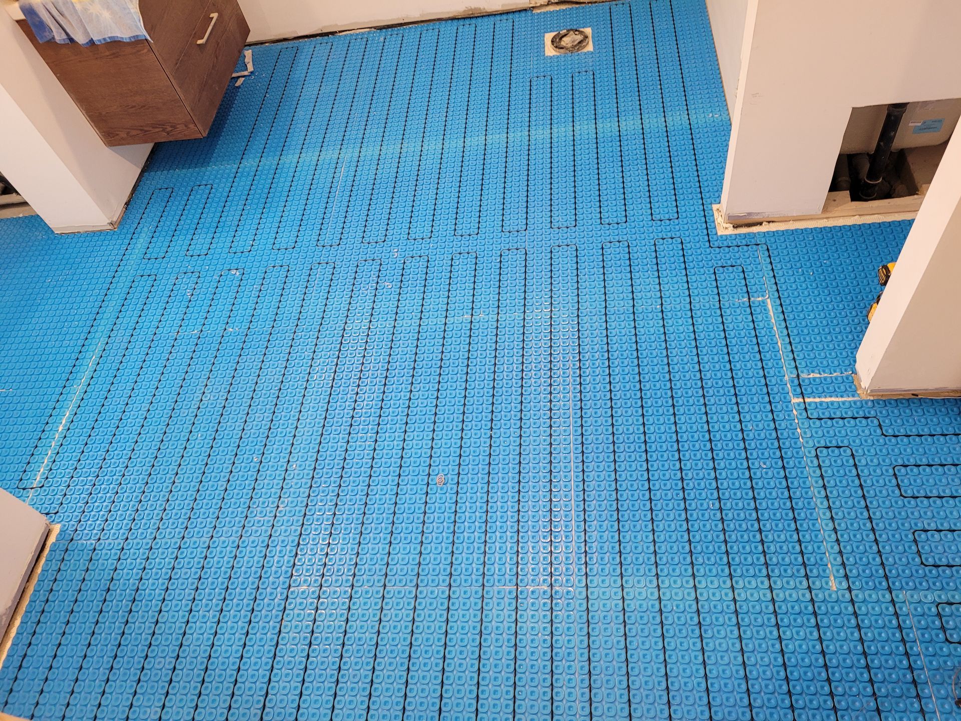 Un sol en carrelage bleu est en cours d'installation dans une pièce.