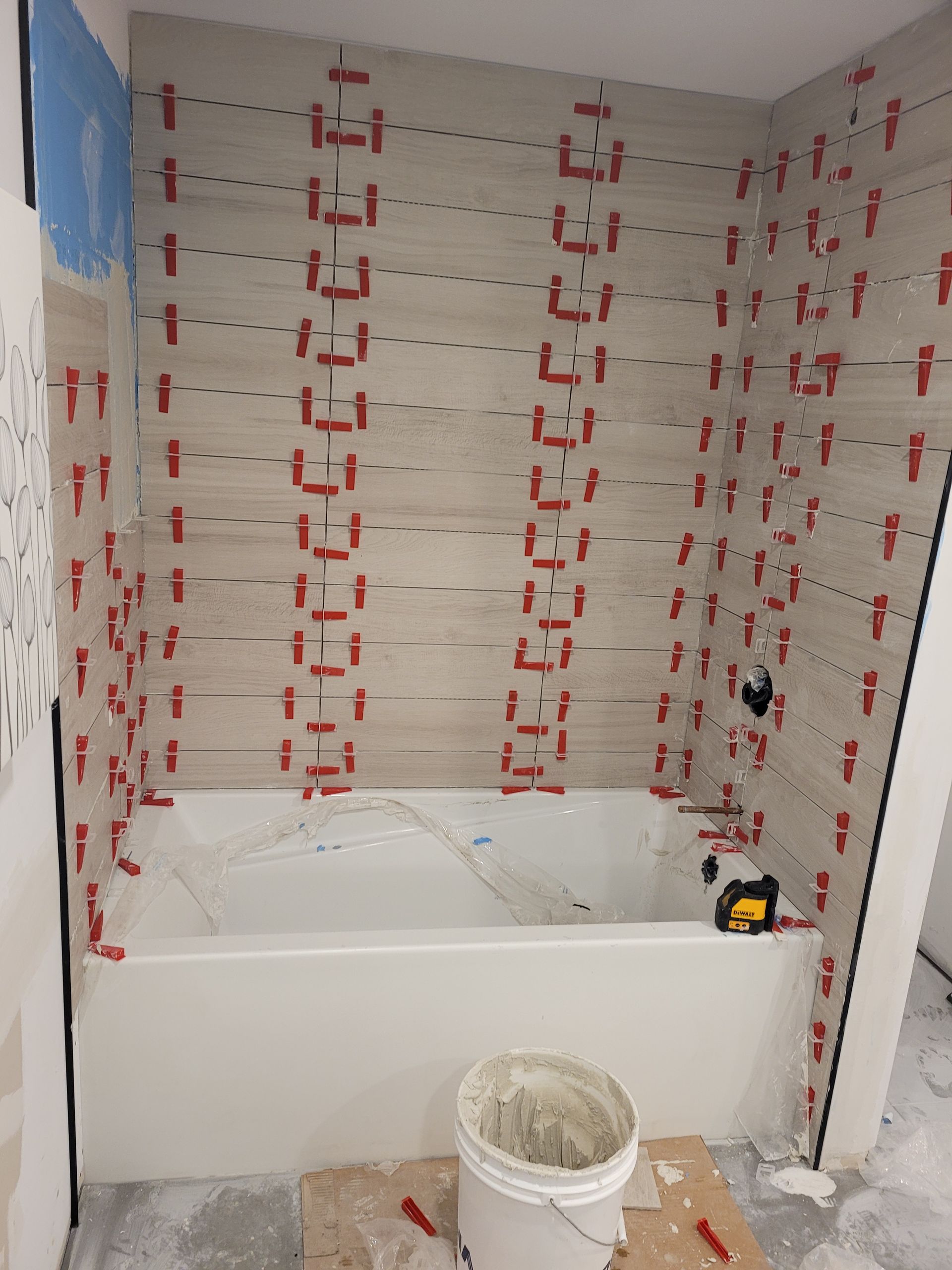 Une baignoire est en cours de construction dans une salle de bain avec du carrelage au mur