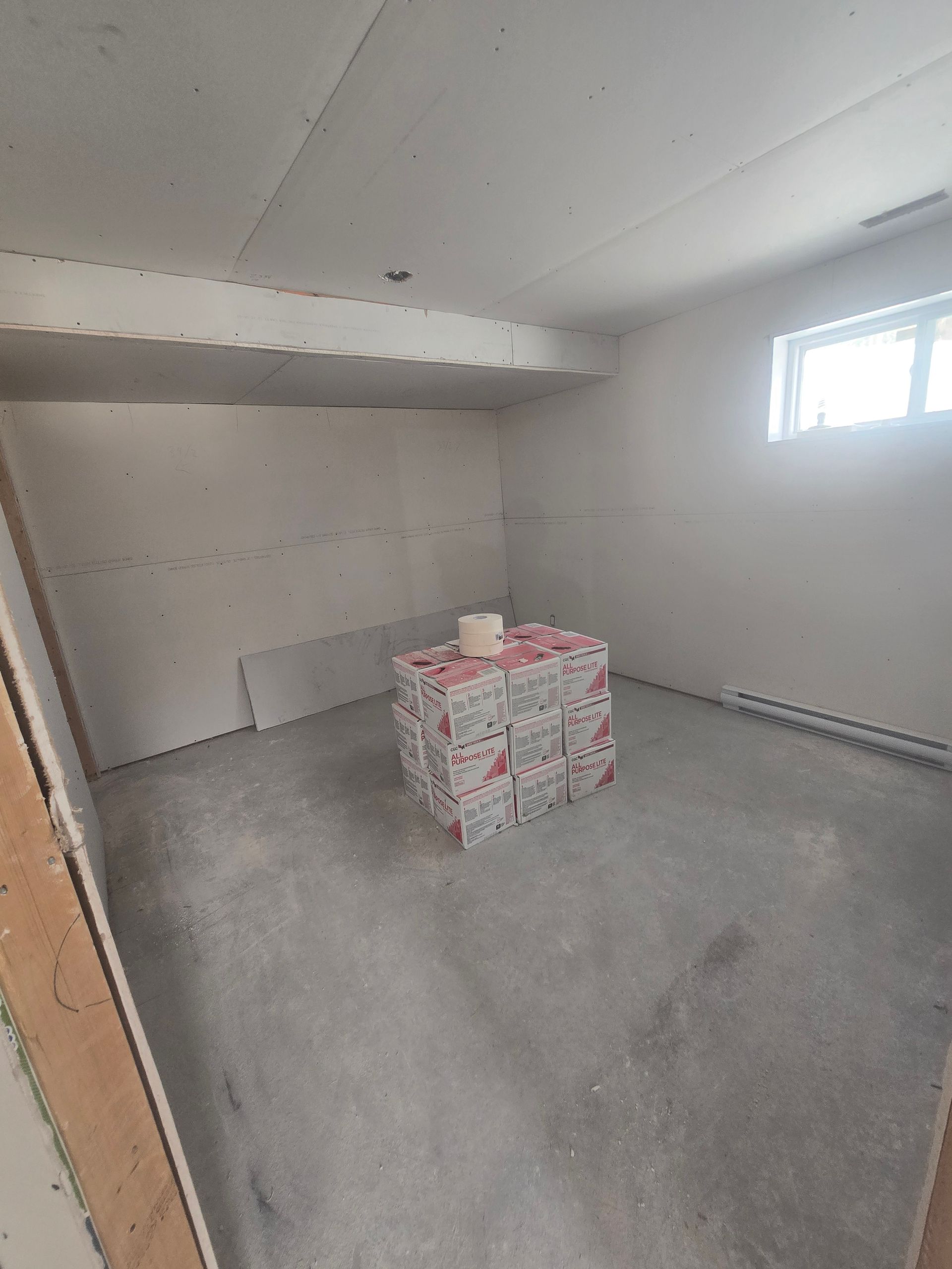 Une pièce avec une pile de boîtes sur le sol et une fenêtre.