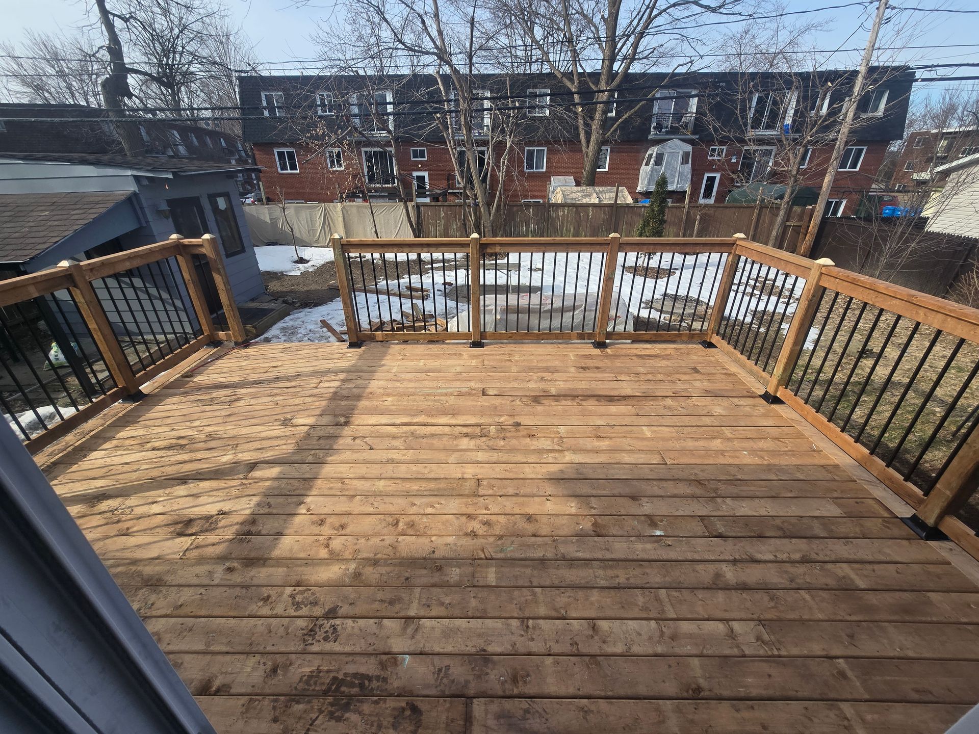 Une terrasse en bois avec une balustrade en métal et des escaliers qui y mènent.