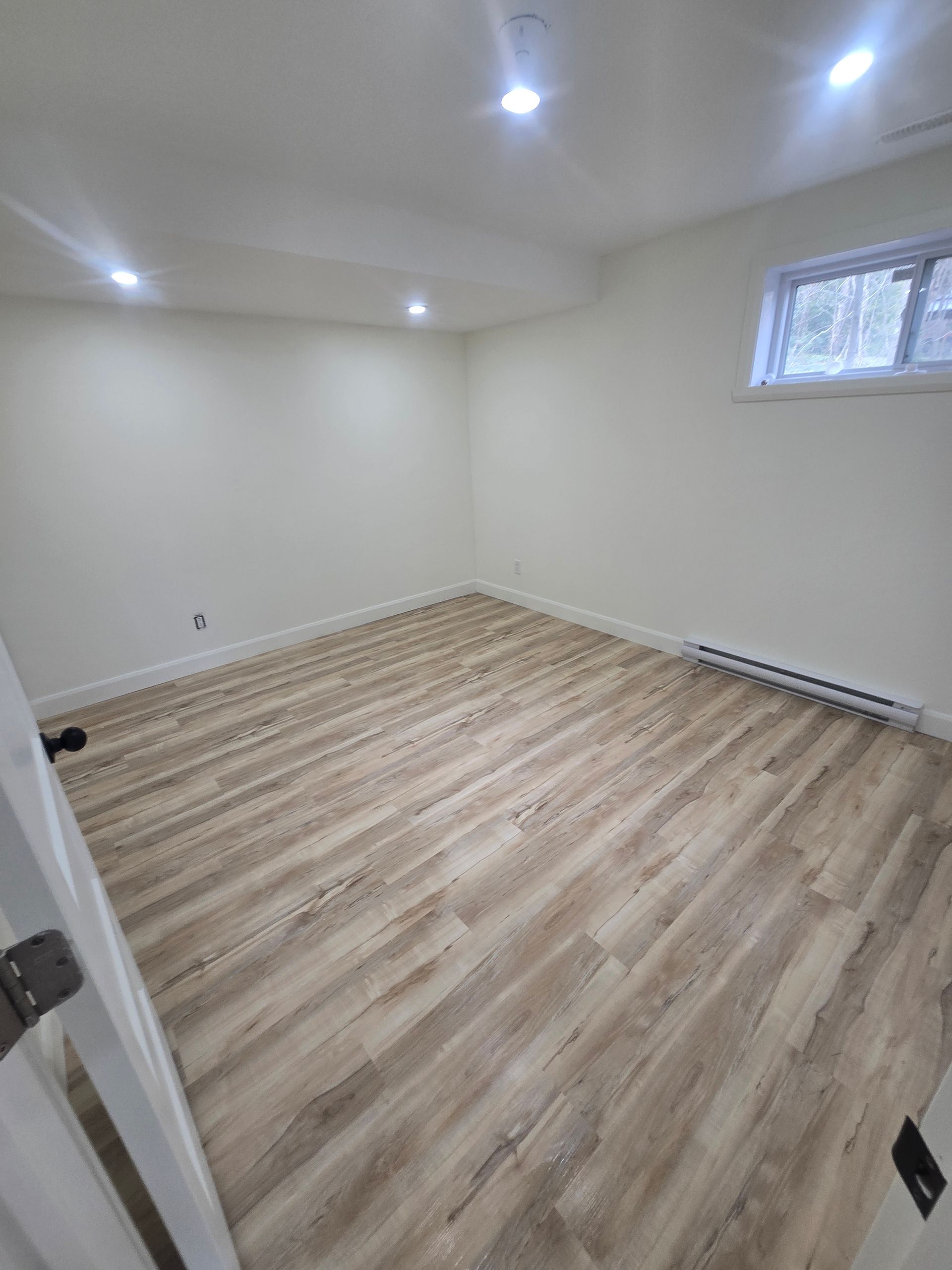 Une pièce vide avec du parquet et des murs blancs.