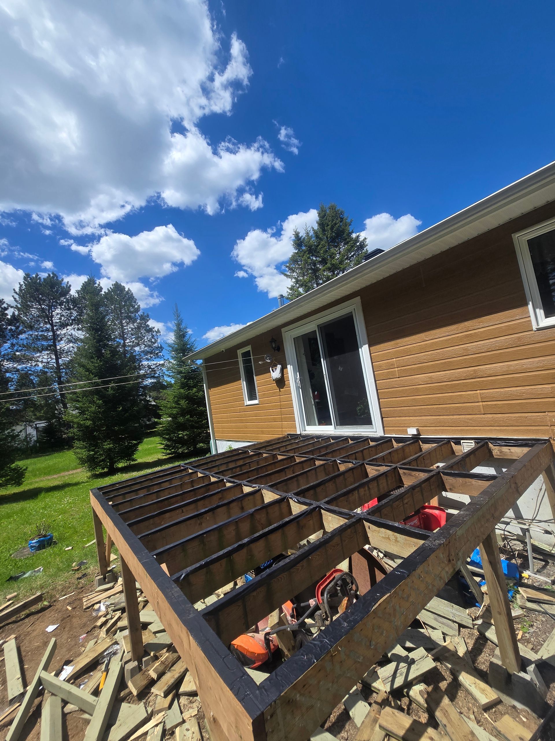 Une terrasse en bois est en cours de construction devant une maison.