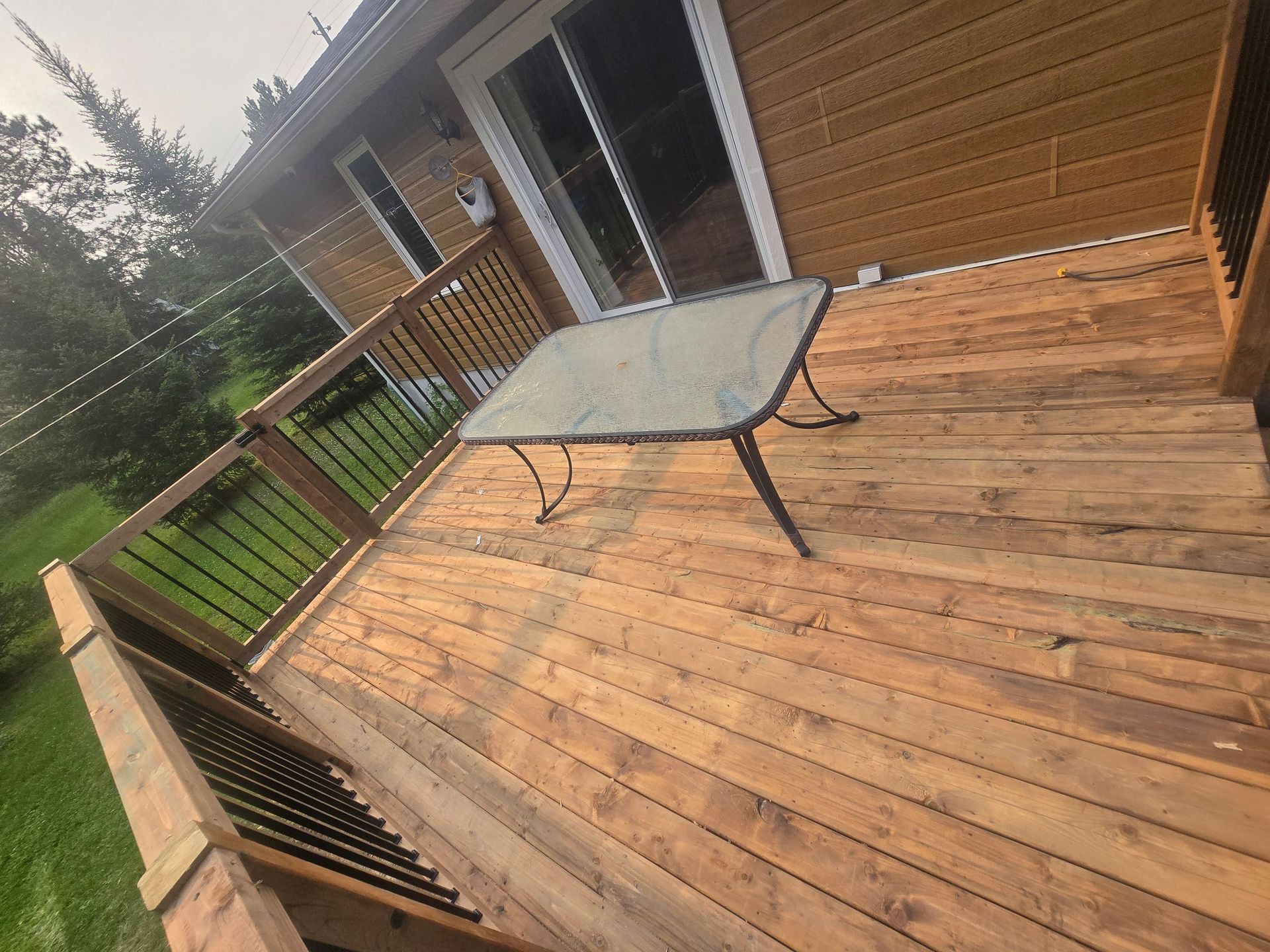 Une terrasse en bois avec une table et des chaises devant une maison.