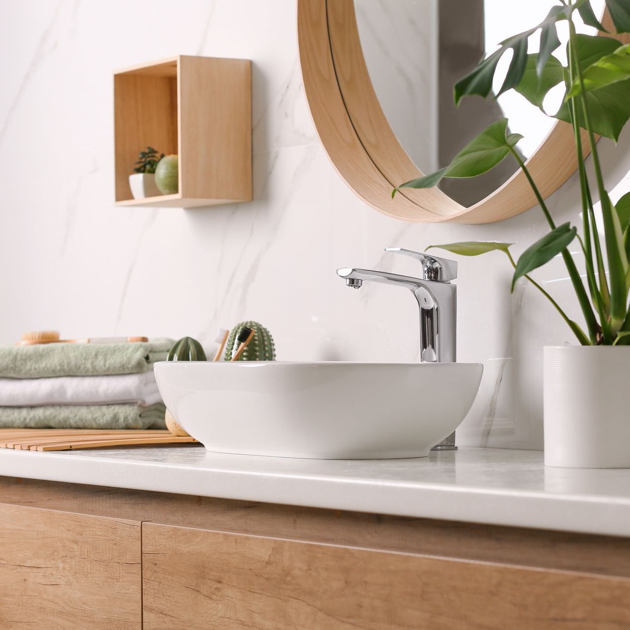 Une salle de bain avec un lavabo, un miroir et une plante