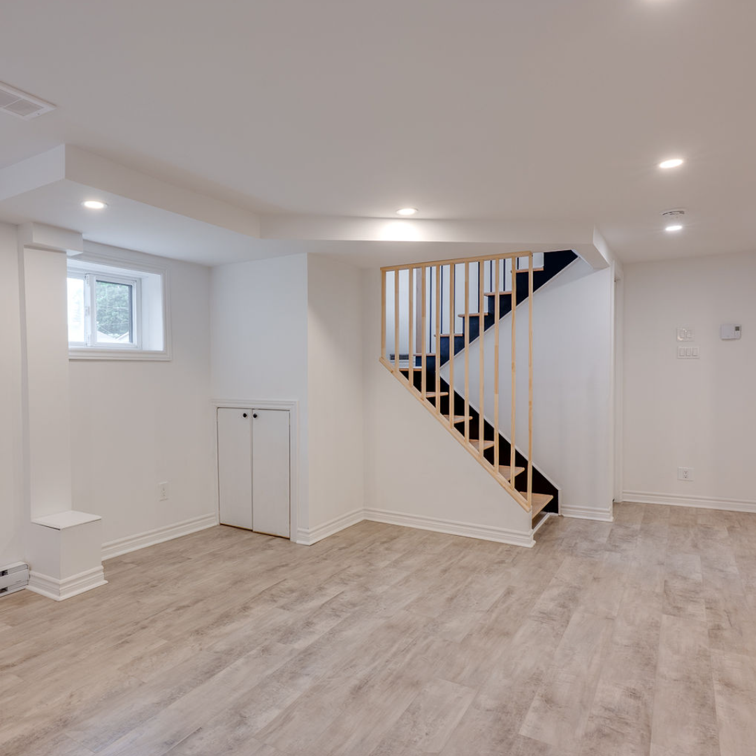 Une pièce vide avec un escalier en bois et une fenêtre