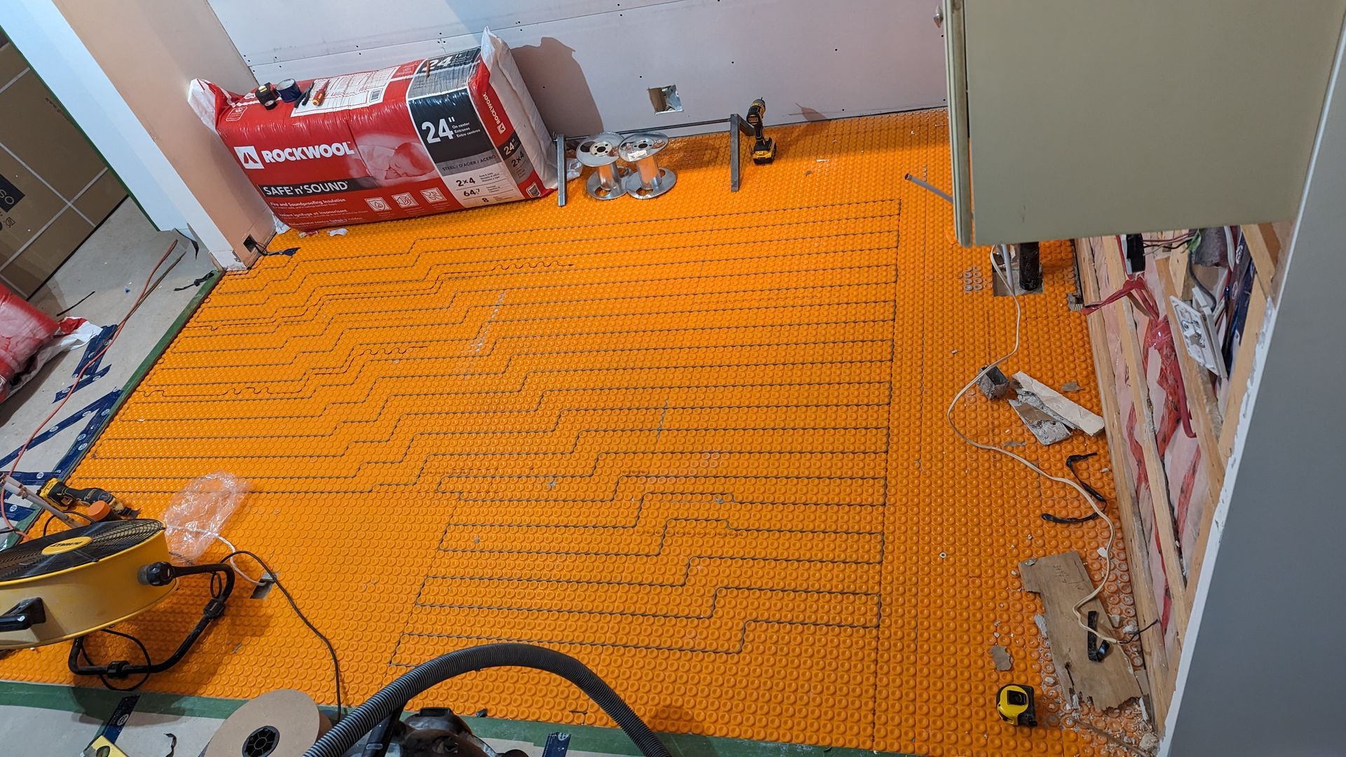 Une pièce avec beaucoup de moquette orange et un aspirateur sur le sol.