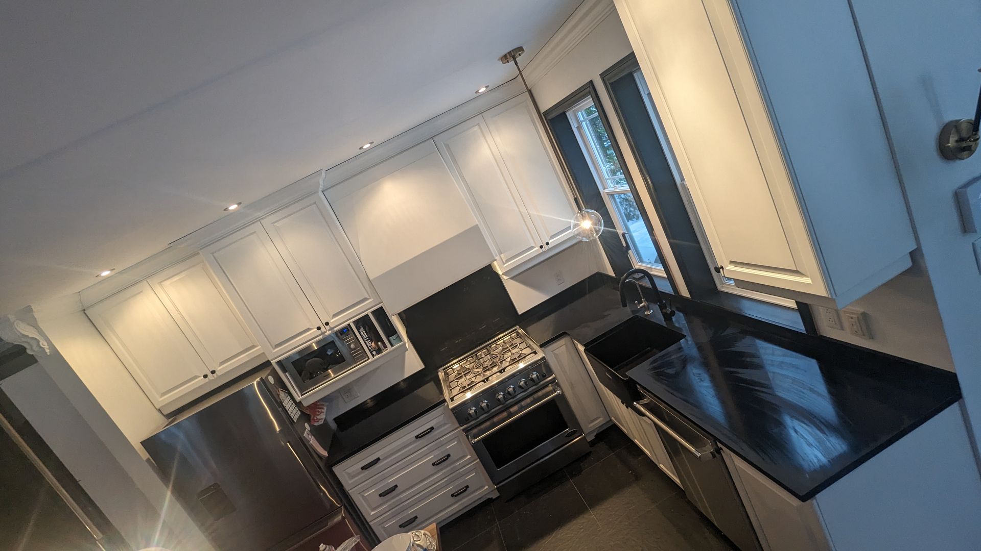 Une cuisine avec des armoires blanches, des appareils en acier inoxydable et un comptoir noir.