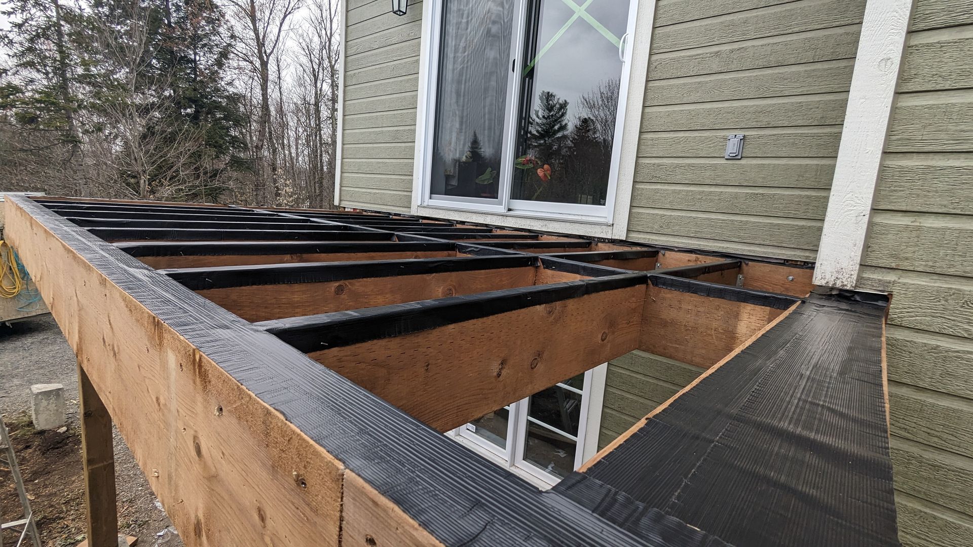Une terrasse en bois est en cours de construction sur le côté d'une maison.