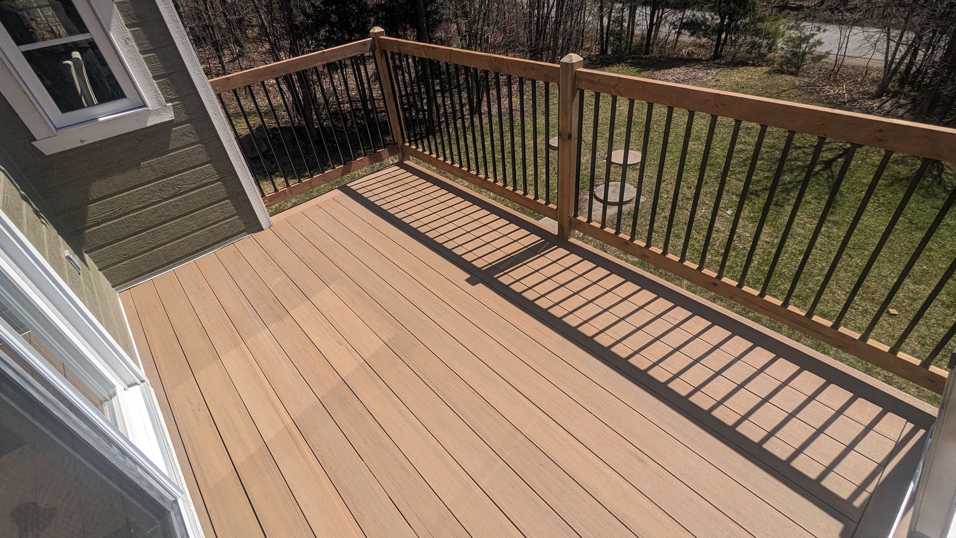 Une terrasse en bois avec une balustrade en métal et une fenêtre.