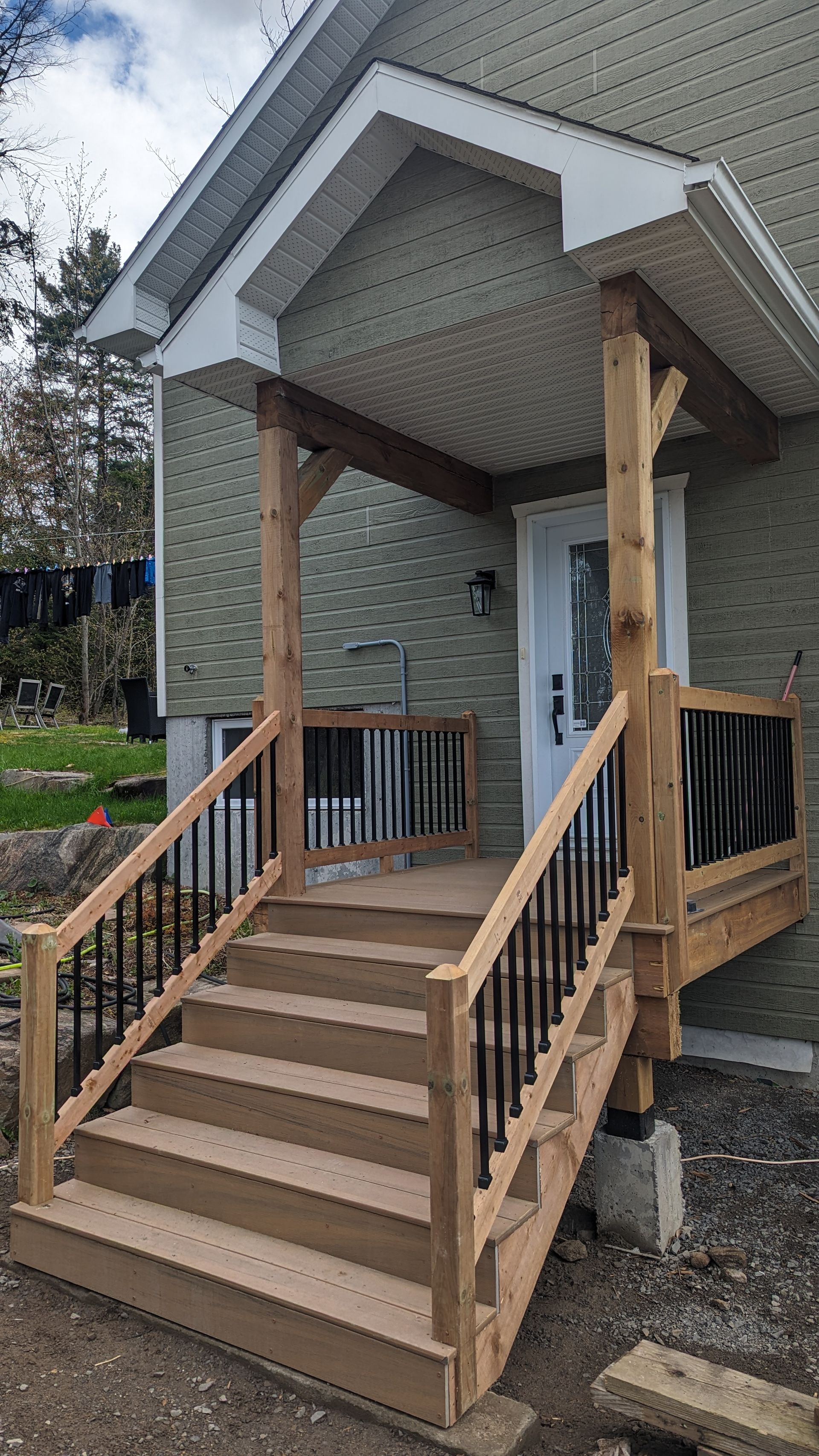 Un porche en bois avec des escaliers menant à la porte d'entrée d'une maison.
