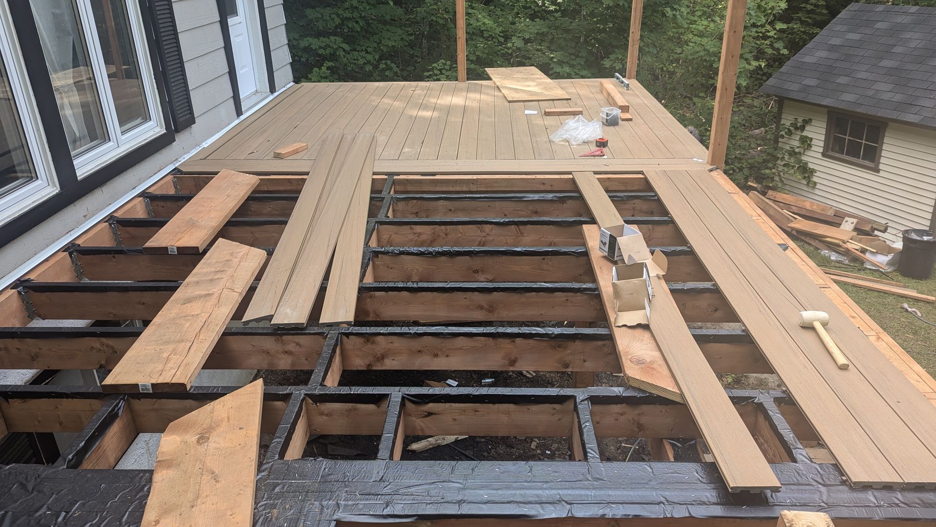 Une terrasse en bois est en cours de construction devant une maison
