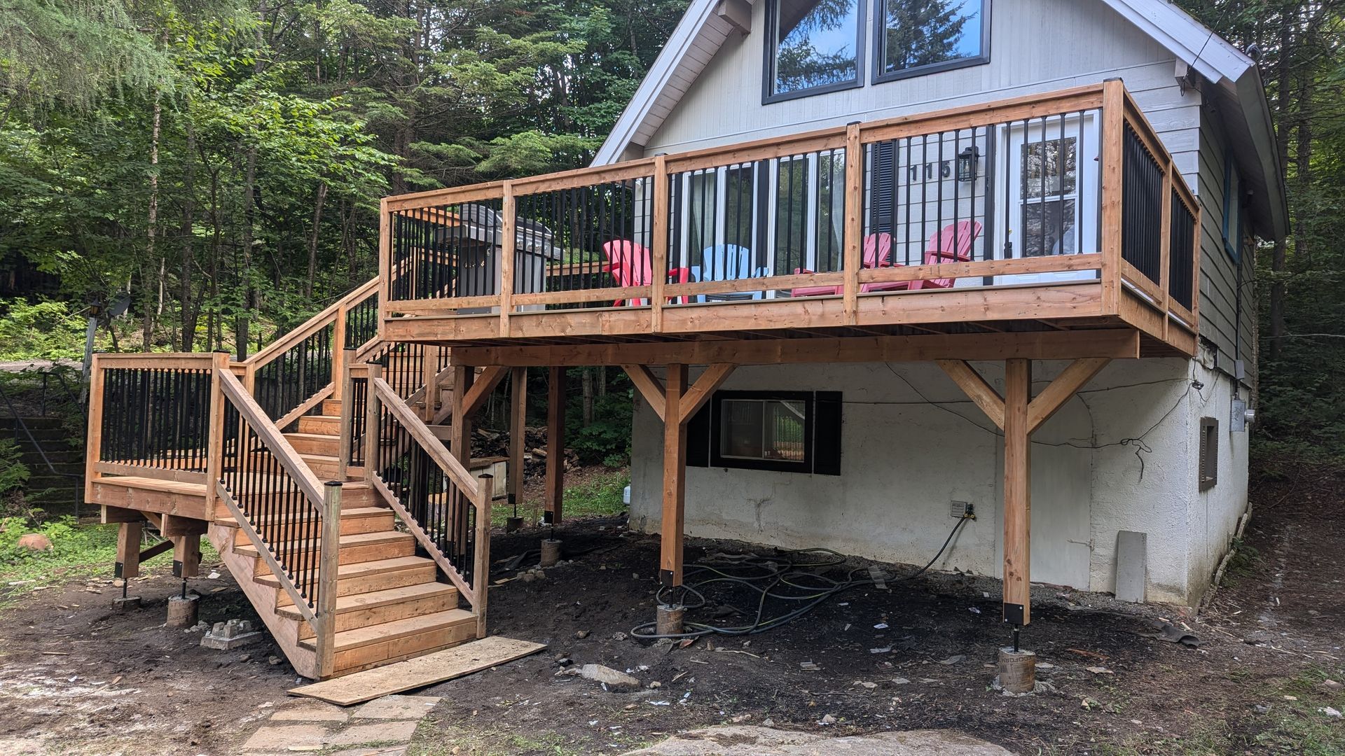 Une maison blanche avec une grande terrasse en bois et des escaliers.