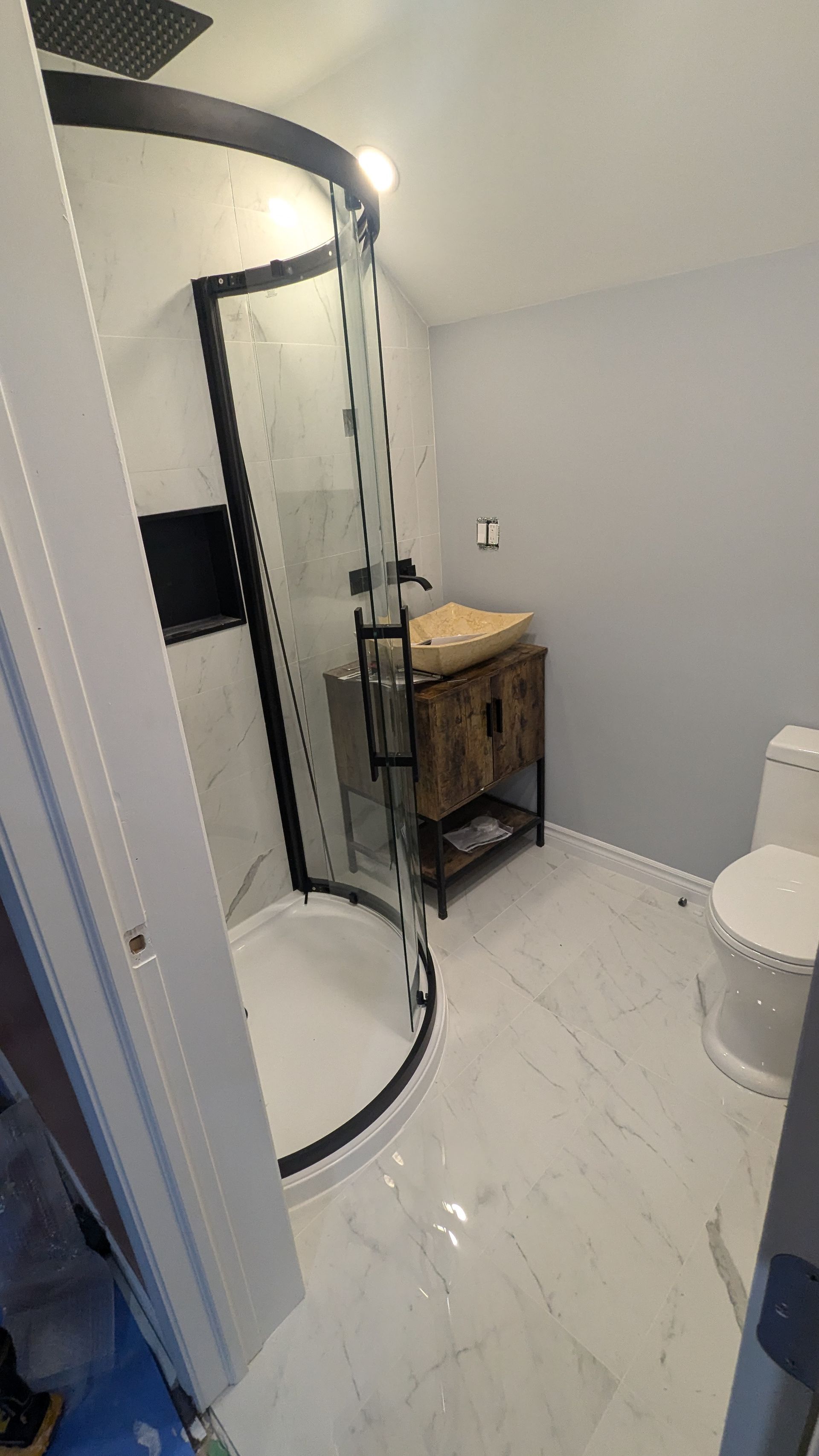 Une salle de bain avec douche, lavabo et WC.