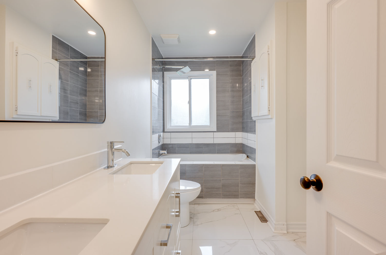 Une salle de bain avec lavabo, WC, baignoire et miroir.