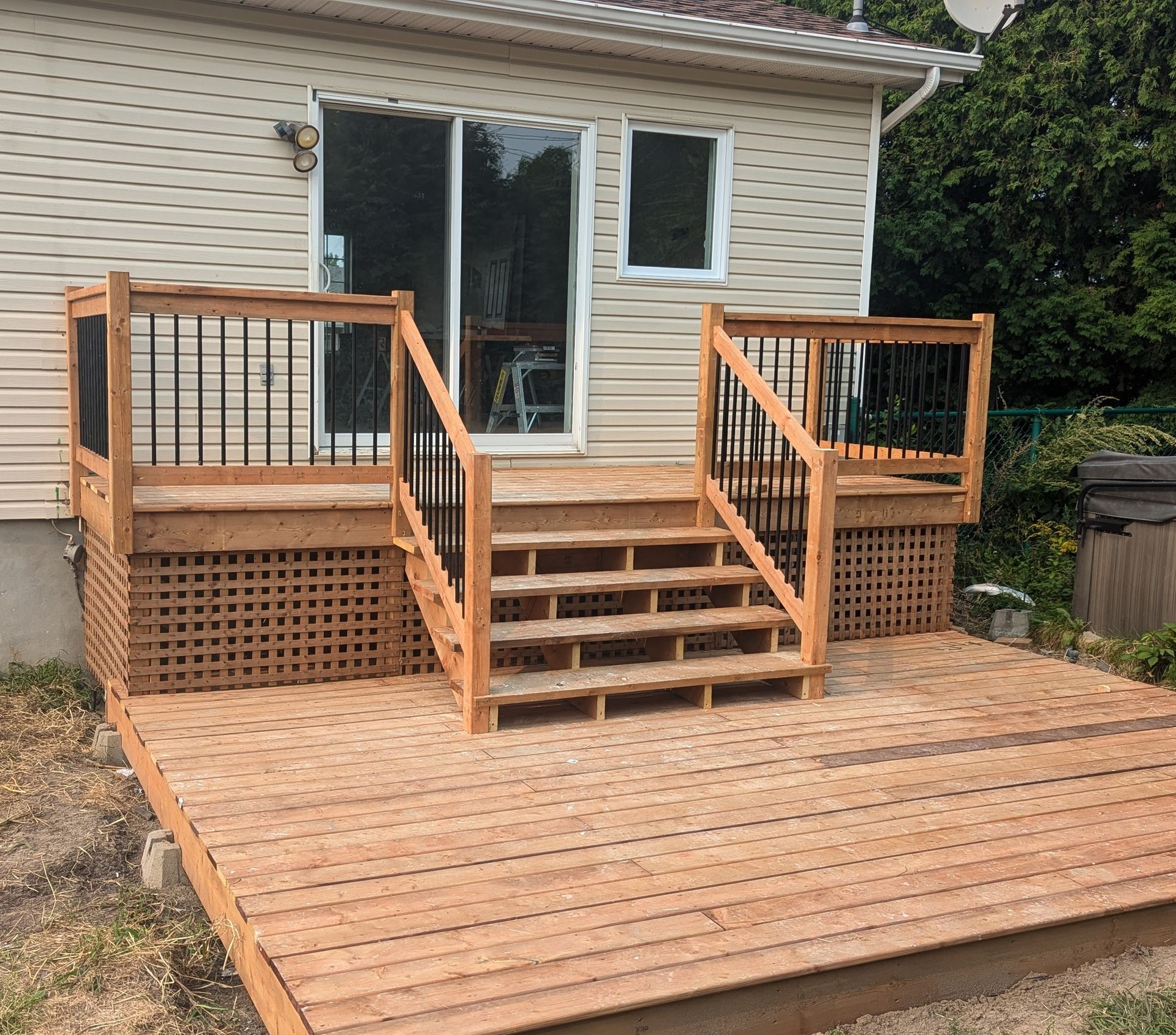 Une terrasse en bois avec des escaliers se trouve devant une maison.