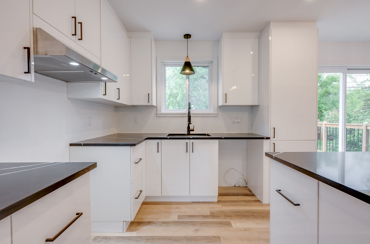 Une cuisine avec des armoires blanches et des comptoirs noirs