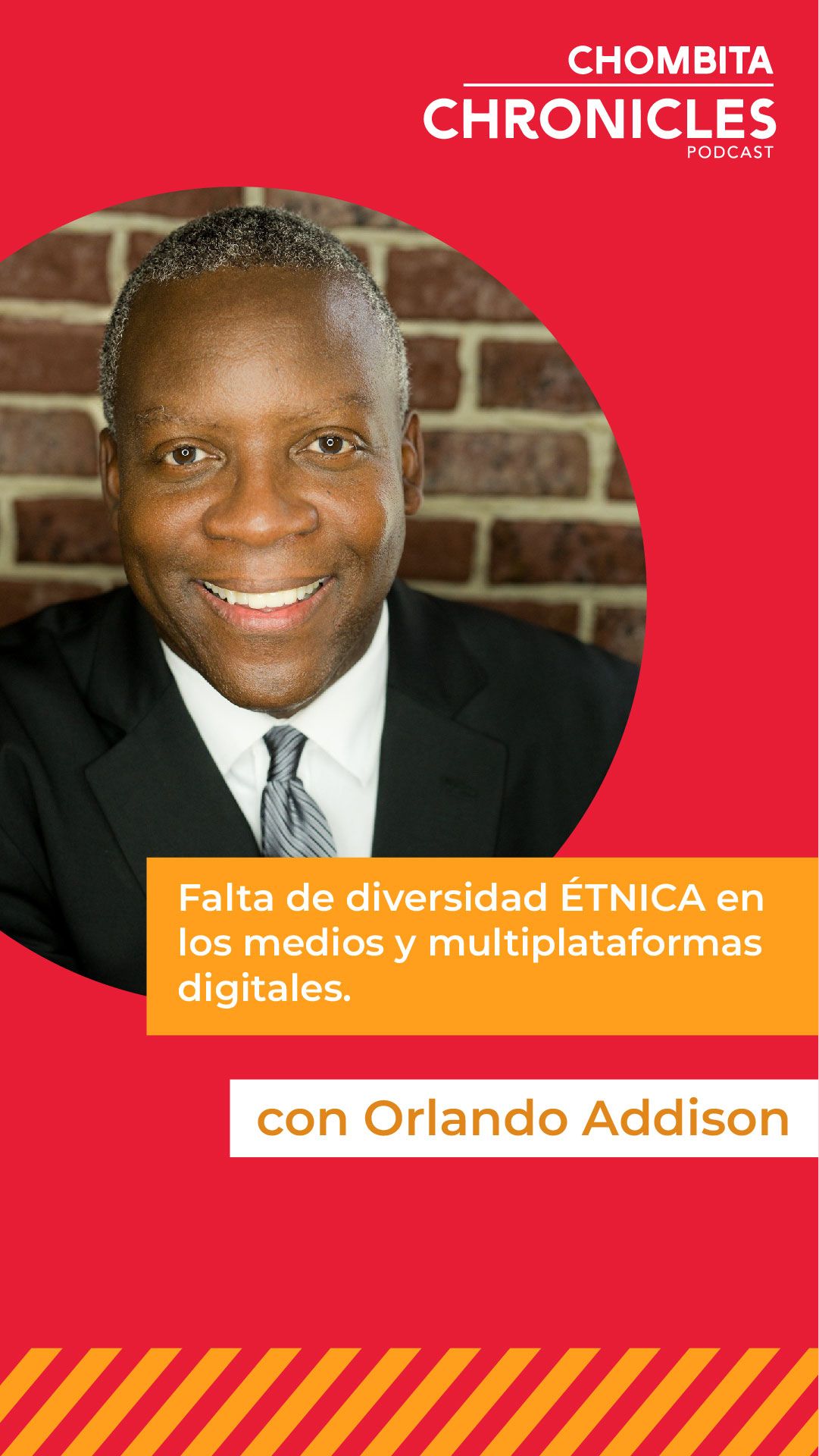 A man in a suit and tie is smiling in front of a brick wall.