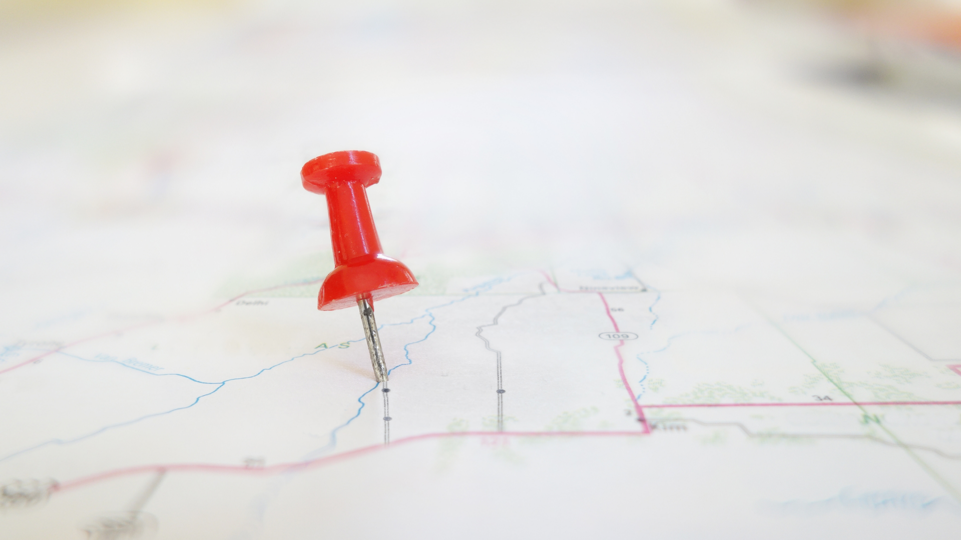 A red pin is sitting on top of a map.