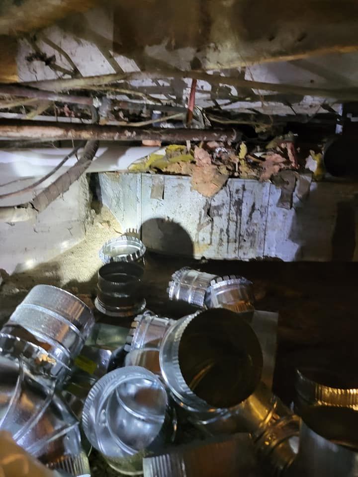 A bunch of metal pipes are stacked on top of each other in a basement.