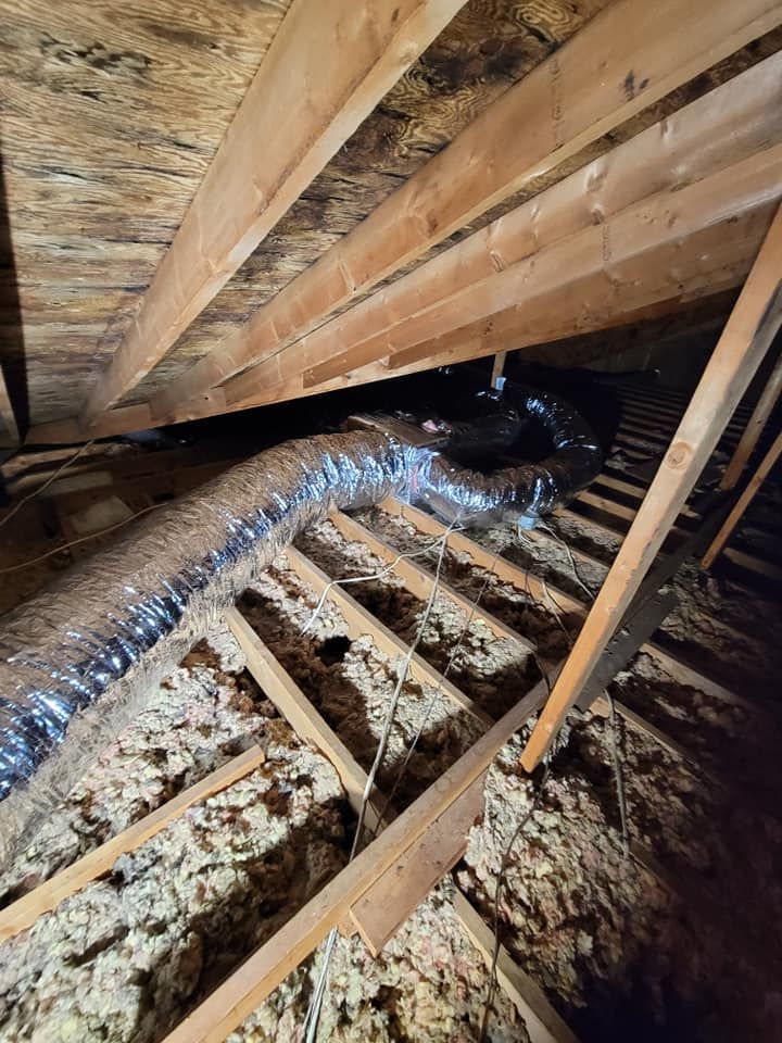 There is a duct in the attic of a house.
