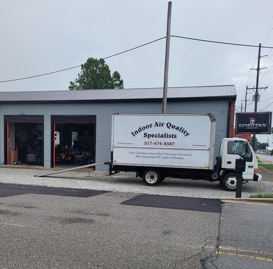 An indoor air quality truck is parked in front of a building