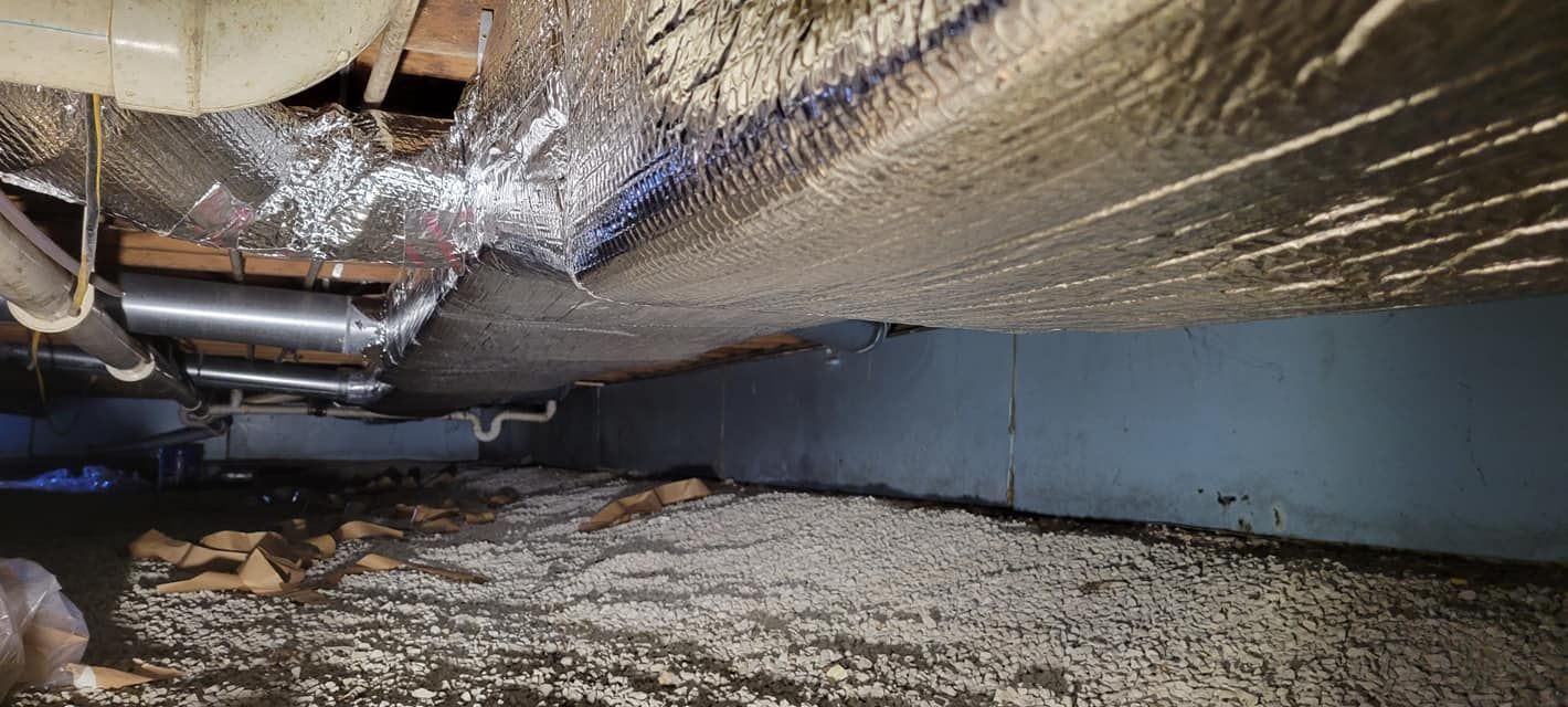 The bottom of a basement with a lot of insulation and pipes.