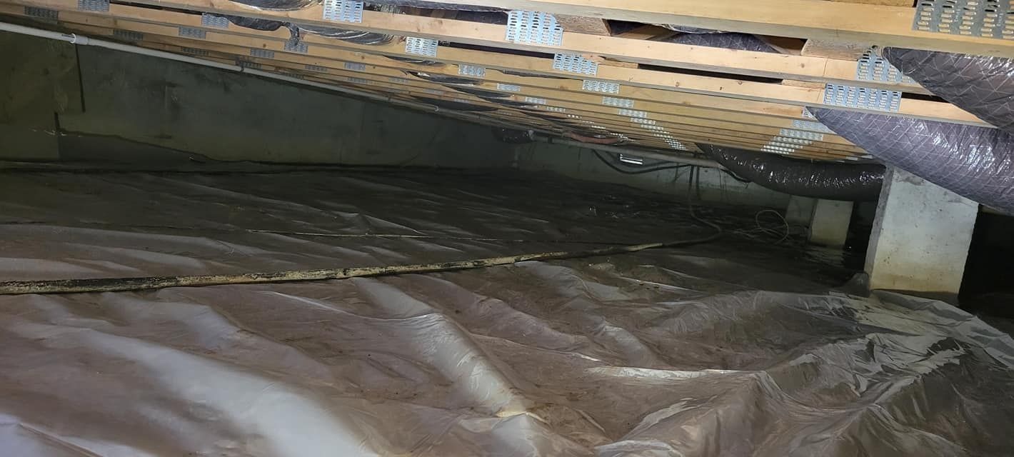 A close up of a crawl space covered in plastic.