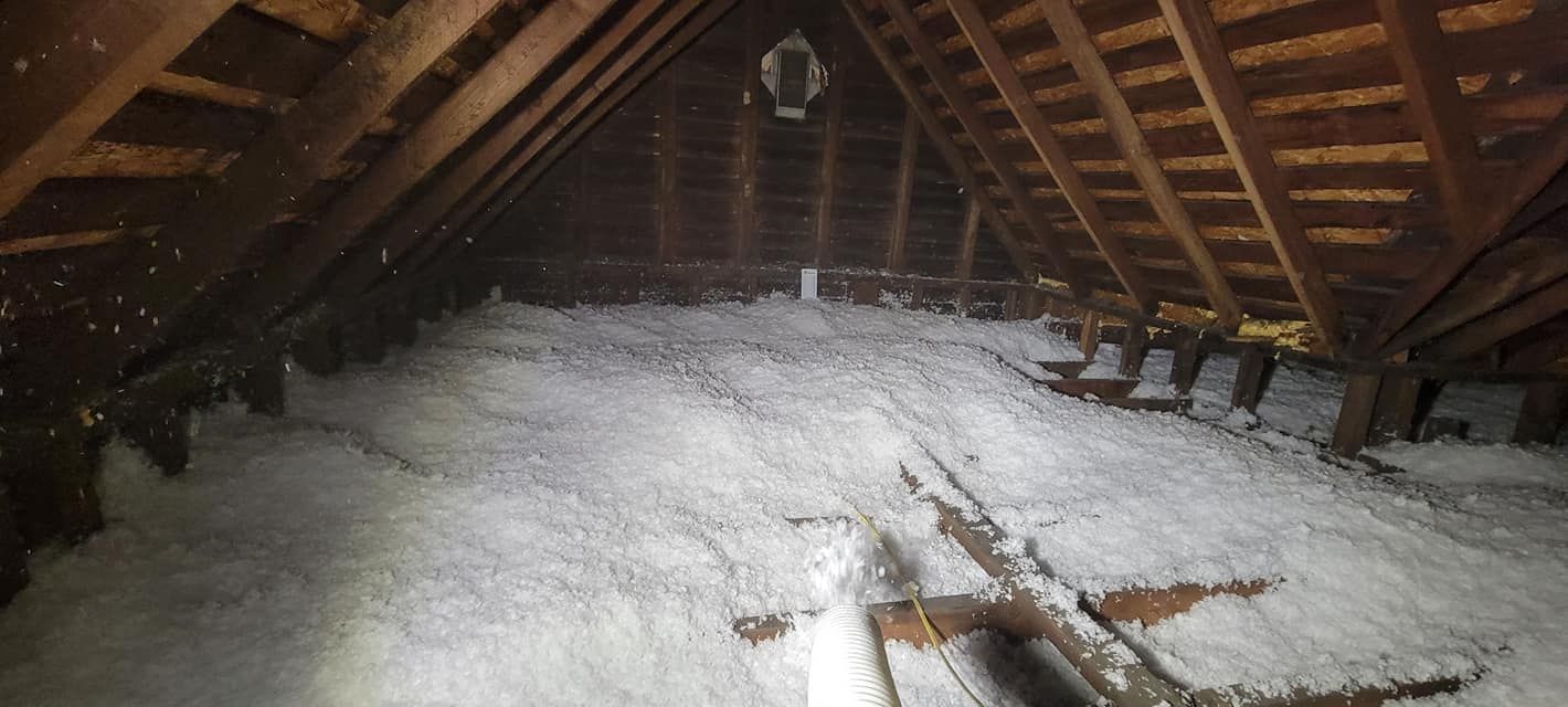 A dark attic filled with lots of white insulation.