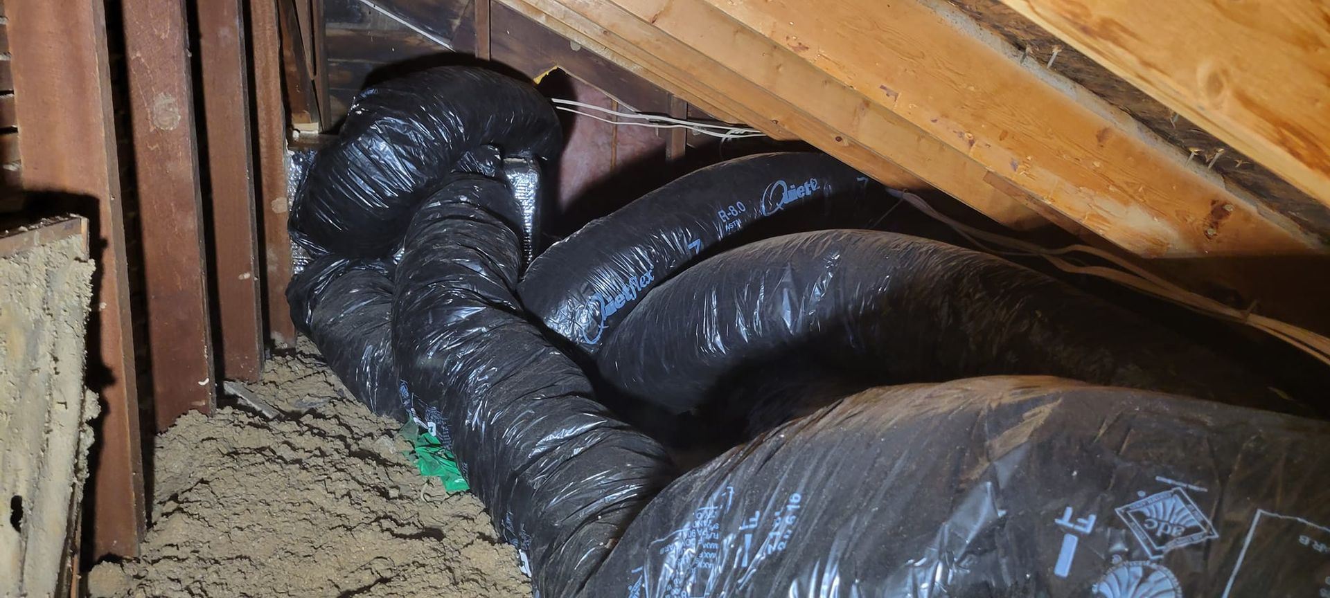A bunch of black bags are stacked on top of each other in a room.