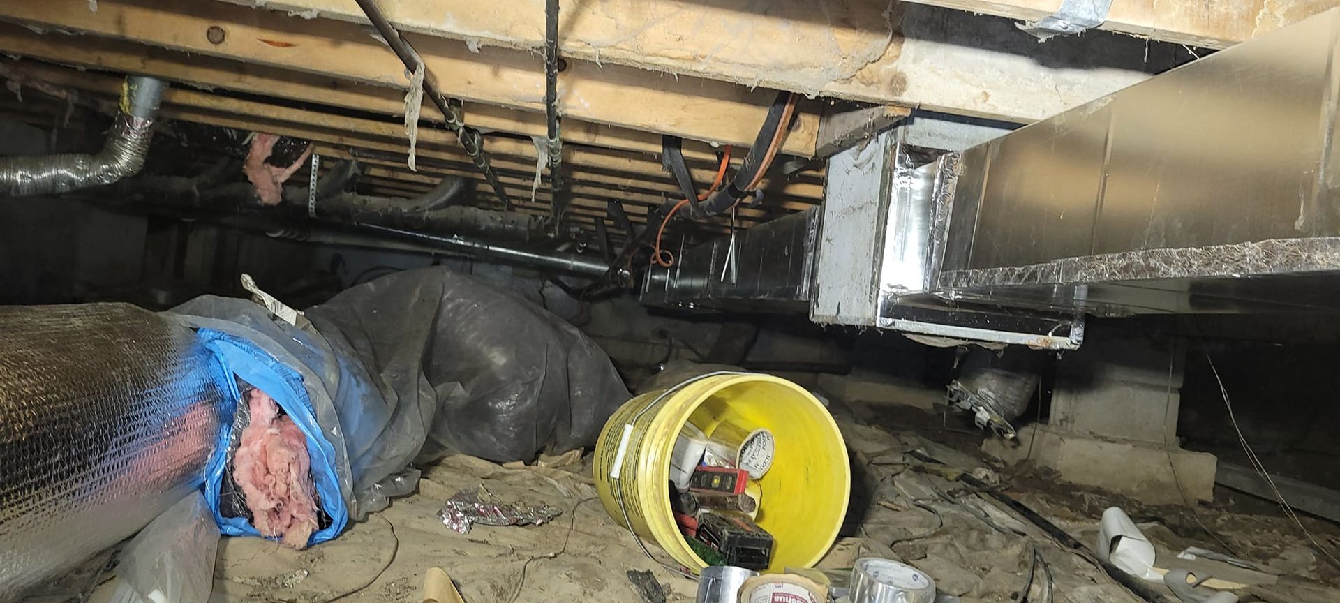 A yellow bucket is sitting on the ground in a basement.