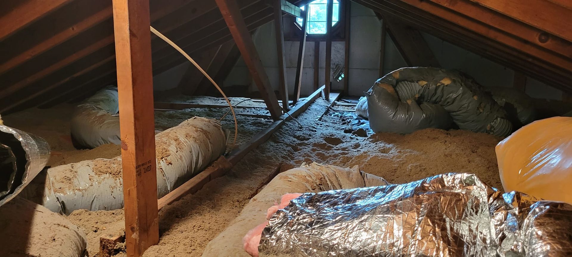 An attic with a lot of ducts and insulation