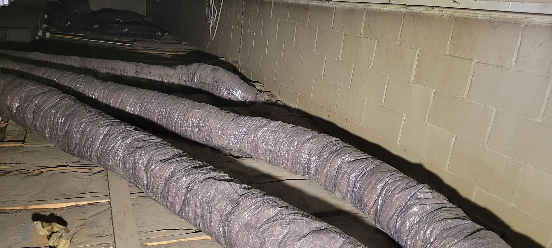 A bunch of ducts are laying on the floor in a basement.